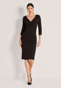 Zwarte, getailleerde jurk met een diepe V-hals, driekwart mouwen en ruchingdetails. Gemaakt van een licht gestructureerd materiaal, knielang.