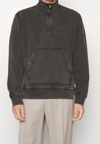 Mörkgrå huvtröja i mjuk bomull, har en hög krage med halvmatchande dragkedja, framficka och ribbade ärmslut och nederkant.