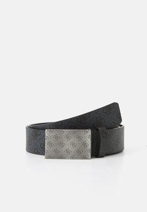 Ceinture en cuir noir avec une boucle rectangulaire en argent gravée d’un motif décoratif répétitif de logo, présentée enroulée sur une surface blanche.
