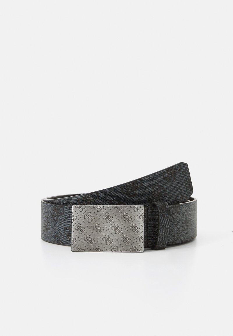Ceinture en cuir noir avec une boucle rectangulaire en argent gravée d’un motif décoratif répétitif de logo, présentée enroulée sur une surface blanche.