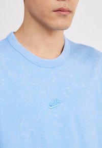 Γαλάζιο Nike μπλουζάκι με στρογγυλή λαιμόκοψη, μαλακή υφή και κεντημένο λογότυπο στο στήθος. Το σχέδιο διαθέτει μια διακριτική, ξεθωριασμένη εμφάνιση.