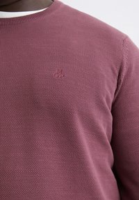 Sweter robiony na drutach w kolorze burgundowym z fakturowanym wzorem. Posiada okrągły dekolt i subtelne logo wyszyte na piersi.