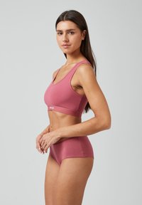Roze katoenen sportbeha en bijpassende hipsteronderbroek met een naadloos ontwerp, brede bandjes en een logo op de band. Gladde textuur.
