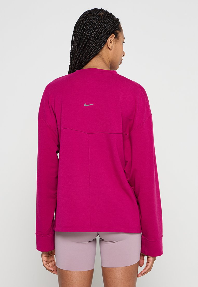 Sudadera de manga larga magenta con cuello redondo, que presenta un logo reflectante de Nike en la parte superior de la espalda y un ajuste relajado.