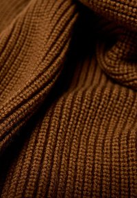 Pull en tricot marron avec une texture côtelée, fabriqué dans un tissu doux et épais, doté d'un col roulé confortable. Motif subtil et chaleur évidente.