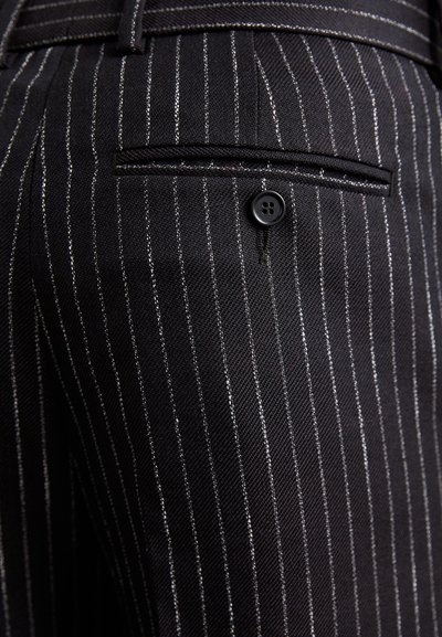 Black pinstripe trousers featuring a textured fabric, side pocket with a button closure, and a sleek tailored fit.