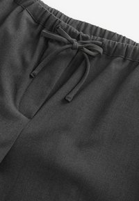 Shorts gris charbon en tissu doux, dotés d'une taille élastique avec cordon de serrage et d'une petite ouverture sur le devant.