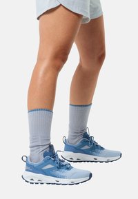 Blauwe sportieve schoenen met een ademend mesh bovenwerk en een stevige rubberen zool, gecombineerd met lichtgrijze geribde sokken. Modern ontwerp, sportieve uitstraling.