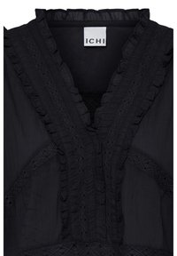 Blouse noire avec un décolleté en V profond, dotée d'un galon à volants et d'empiècements en dentelle le long de l'encolure et de la poitrine, étiquetée "ICHI."