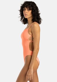 Maillot de bain une pièce côtelé pêche avec encolure carrée, découpes sur les côtés et fines bretelles, doté d'une texture de tissu lisse.