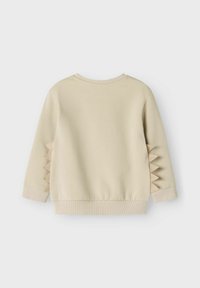 Felpa in cotone beige con maniche lunghe, polsini a coste e un motivo a zigzag testurizzato sui lati. Finitura liscia, scollatura a girocollo.