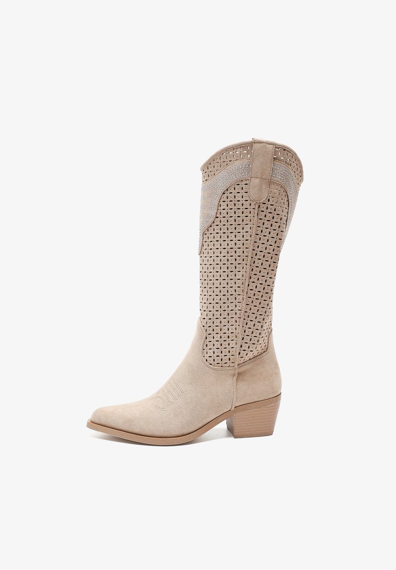 Bota de vaquero de ante beige con parte superior perforada, punta afilada y tacón apilado. La costura decorativa a lo largo de los laterales añade detalle.