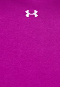 Tissu magenta éclatant avec un petit logo blanc Under Armour centré près du bord supérieur.