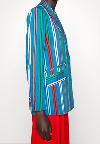 Gestreepte blazer in blauw, groen, rood en wit; met een reverskraag, een enkele borstzak en gedetailleerde mouwafwerking.