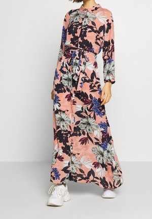 Vestido largo de tela suave con base rosa y grandes patrones florales en negro, blanco y azul, mangas largas y cinturón en la cintura.