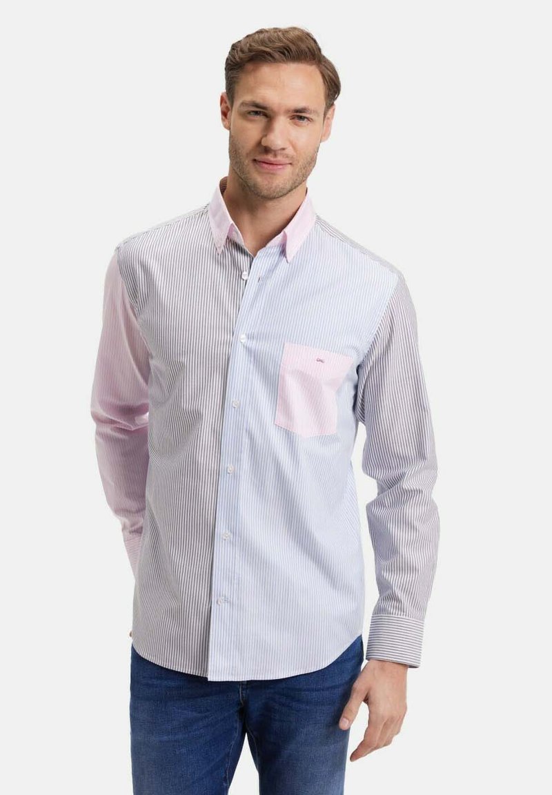 Chemise à rayures avec un schéma de couleurs bleu clair et rose. Présente un col et une poche rose. Le tissu semble lisse. Portée par-dessus un jean.
