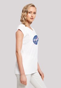 White short-sleeve t-shirt featuring a blue NASA logo design. The fabric appears soft and lightweight with a relaxed fit.