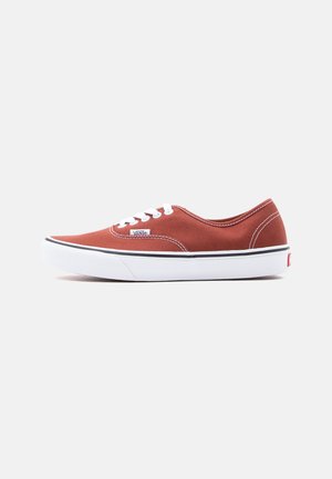 Pantof sport Vans de culoare roșu ruginiu, de tip low-top, cu șireturi albe, talpă albă, dungă neagră și logo-ul Vans pe lateral și călcâi, prezentat în profil drept.