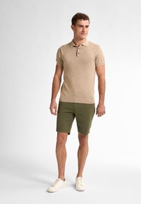 Beige poloko s krátkým rukávem a tříknoflíkovým zapínáním, spárované s olivově zelenými kraťasy a bílými teniskami. Jednoduchý design a ležérní střih.