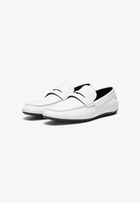 Bijele kožne loferice sa zaobljenim vrhom, crnim unutarnjim podstavljanjem i suptilnim detaljima šivanja. Model na slip-on sa ravnim gumiranim đonom.