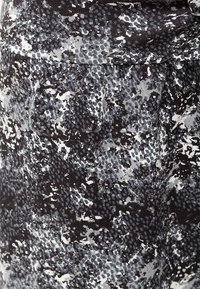 Svart och grå mönstrad tyg med en texturerad, reptil-liknande design; material av medelvikt med en elastisk kvalitet, lämplig för kläder.