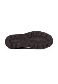 Suela de zapato de goma negra con surcos profundos, bordes redondeados y superficie texturizada. Presenta una impresión de logo en el centro.