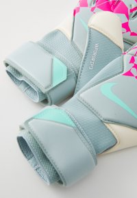 Nike Vapor Grip 3 målvaktshansker i lyseblå med rosa og turkise detaljer. Har teksturert grep, borrelåslukking og forsterkede områder.