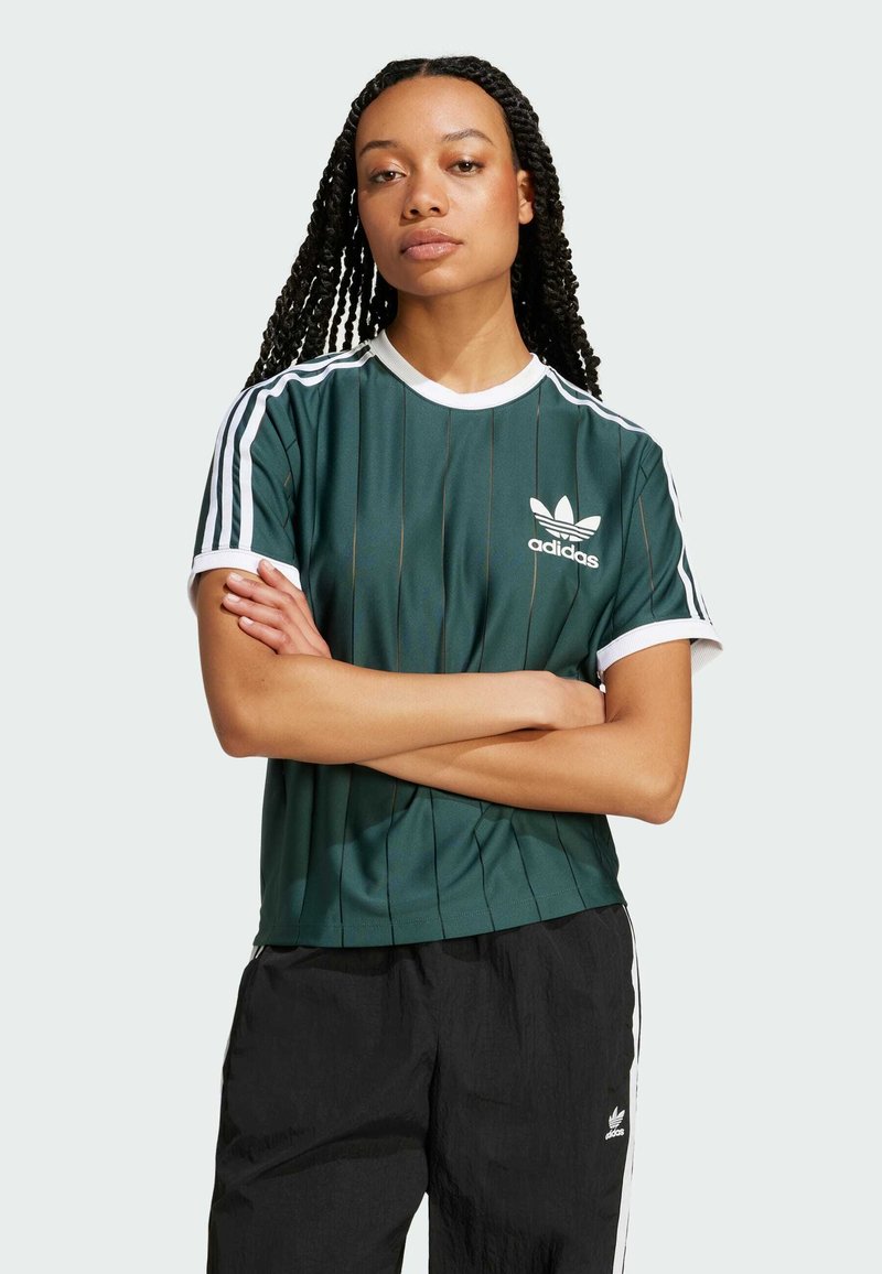 Zielona sportowa koszulka z białymi paskami na rękawach, z pionowymi liniami i logo Adidas na piersi. Miękki materiał, okrągły dekolt.