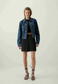 Jeans jakna v temno modri barvi s ovratnikom, z dvema sprednjima žepoma, nosi se čez črn top in krilo, v paru s črnimi sandali na vezanje.