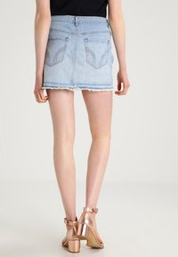 Ljusblå denimminikjol med fransad nederkant, med två bakfickor och en kroppsnära passform. Kombinerad med blockklacksandaler i roséguld.