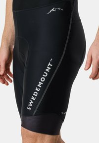 Svarta cykelbyxor med vadderad sits, med vit "SWEDEMOUNT" logotyp, slimmad design, texturerade svarta muddar och diskret berggrafik.