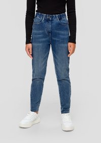 Svijetloplavi traperice s visokim strukom, s prednjim džepovima, s patentnim zatvaračem i suženim nogavicama, uparene s bijelim tenisicama.