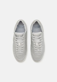 Sneakers in suede grigio con lacci bianchi, punta rotonda e texture morbida. Presentano una soletta ammortizzata e un piccolo logo sulla linguetta.