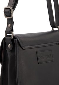 Sort læder skuldertaske med en tekstureret overflade, sølvhardware, justerbar strop og et frontmærke prægede med "VENEZIA."