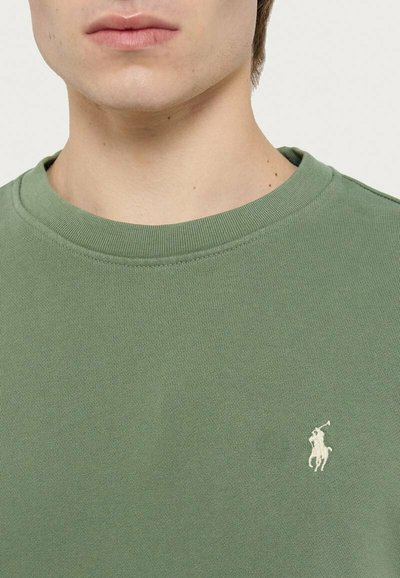 Felpa verde in cotone con scollo rotondo, caratterizzata da un piccolo logo bianco ricamato sul petto sinistro, tessuto strutturato e polsini a costine.