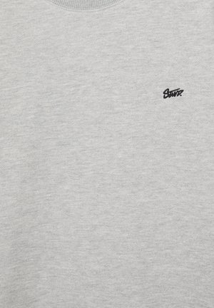 Hellgrauer Stoff mit kleinem schwarzem, besticktem "Santa" Text oben links.