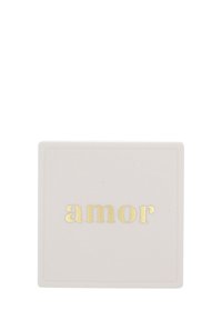 Targa quadrata bianca con la parola "amor" in lettere minuscole dorate centrata su uno sfondo neutro.