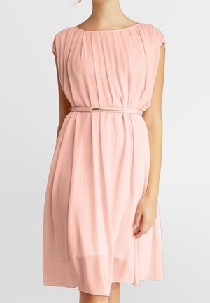 Robe sans manches rose clair, longueur aux genoux, avec des plis, une taille cintrée et une fine ceinture avec une boucle en métal.