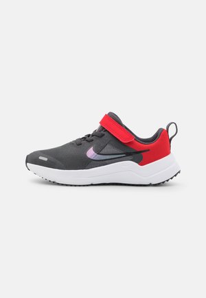 Zapatilla deportiva gris con parte superior de malla, acentos rojos y una correa de gancho y bucle. Media suela blanca y suela de goma negra para tracción.