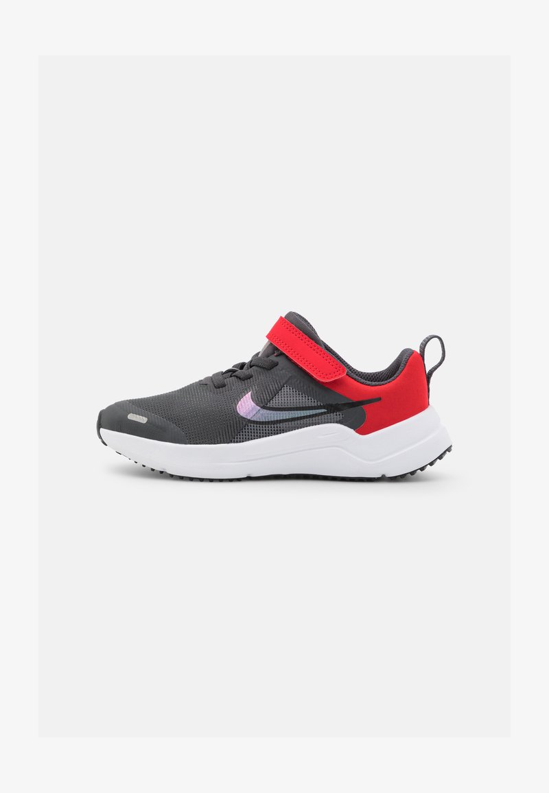 Scarpa da ginnastica grigia con tomaia in mesh, accenti rossi e cinturino in velcro. Suola intermedia bianca e suola in gomma nera per una migliore aderenza.