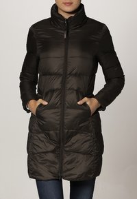 Vadderad svart jacka med hög krage, framdragkedja och sidofickor; har ett quiltat mönster och en snygg design.