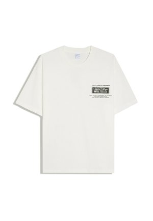 T-shirt blanc à manches courtes avec un petit graphisme noir et blanc et un texte sur le côté gauche de la poitrine indiquant "California Dreams" et "Western Vintage Hotel."