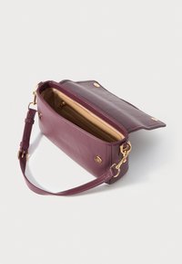 Purple leather crossbody bag with flap open, showing beige interior and gold zipper pocket, and detachable strap with gold hardware.