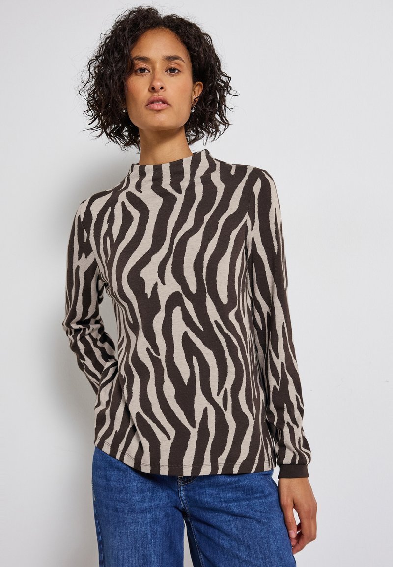 Haut à manches longues en beige clair avec des rayures zèbres foncées, doté d'un col montant et d'une coupe décontractée, fabriqué en tissu doux.