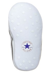 Bílá gumová podrážka s tečkovanou strukturou, obsahující kruhové logo s modrou hvězdou a textem "Converse Chuck Taylor All Star."