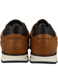 Chaussures en cuir marron avec des accents en cuir noir, dotées d'une semelle blanche rembourrée et de coutures visibles sur le talon. Design simple et arrondi.