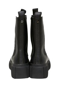 Botas de tobillo negras con un acabado mate, suelas de goma texturizadas y marca distintiva en relieve en los lados. Presentan lengüetas en la parte superior para facilitar su uso.