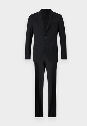 Fekete öltöny, amely egy testhez simuló blézerből áll, két gombbal, kerek nyakkivágással, és illeszkedő, egyenes szárú nadrágból. Sima anyag, minimális díszítéssel.