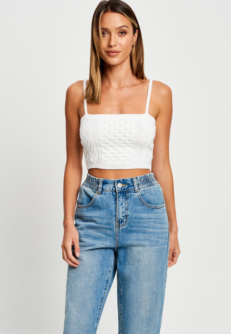 Top corto blanco con patrón de punto texturizado y escote cuadrado, combinado con jeans de tiro alto azul claro que cuentan con una cintura elástica.