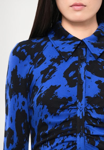 Plava i crna košulja s dugim rukavima uzorčasta, s ovratnikom, zatvaračem na kopčanje i naboranim teksturom duž tijela.